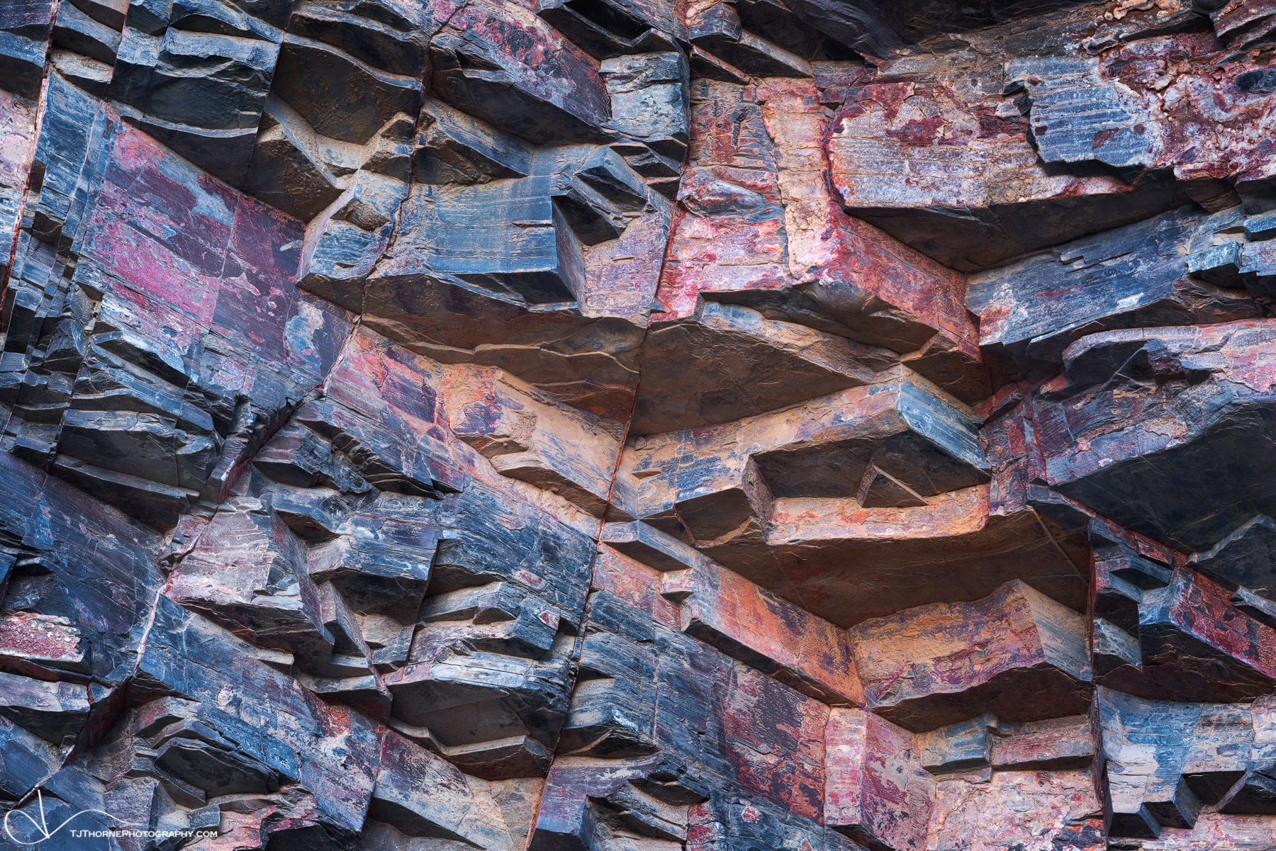 Various colors of desert varnish cover a wall in a remote canyon in Death Valley National Park, California.