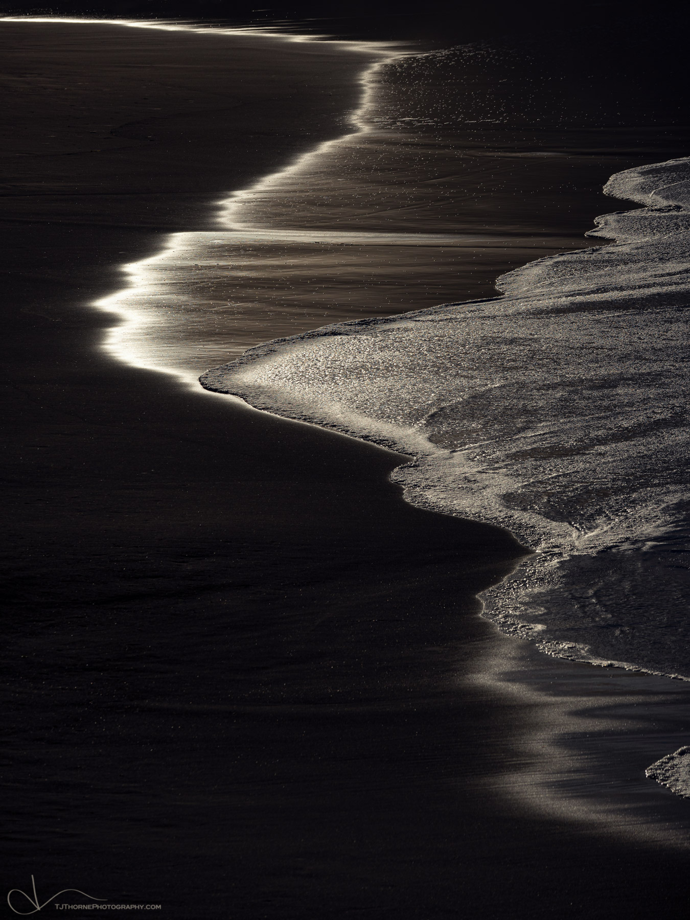 Strong late morning light illuminates the wet sand on Harris Beach in Brookings, Oregon.
